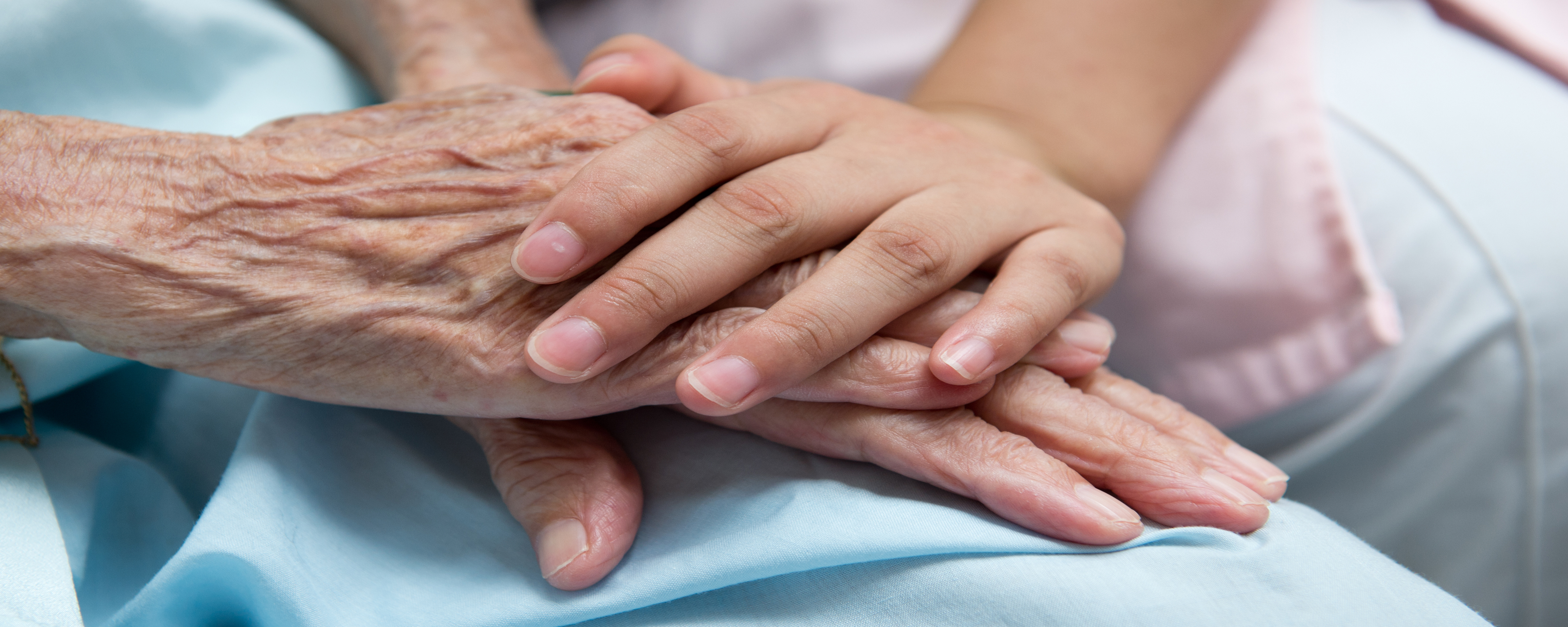 Aging adult and younger person holding hands